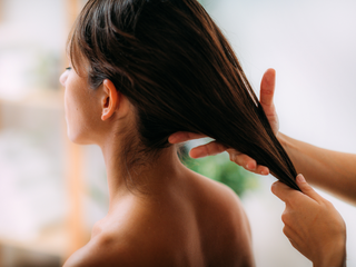 Woman massaging scalp with rosemary oil as part of natural hair growth routine
