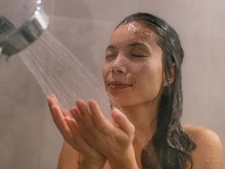 Woman gently adjusting shower temperature for sensitive scalp care